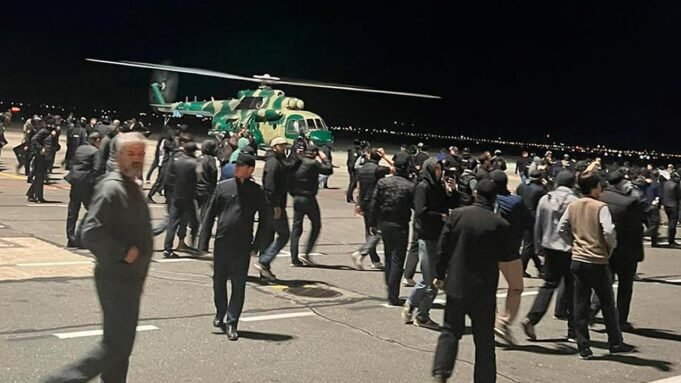 Menschen in der Menge rufen antisemitische Parolen auf einem Flugfeld des Flughafens in Machatschkala, Russland.