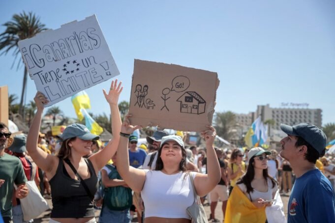 A protester holds a sign reading "Canary Islands have a limit" as thousands march on Las Americas beach during a demonstration against mass tourism, in Arona on the Spanish Canary island of Tenerife, on October 20, 2024. Thousands of flag-waving demonstrators hit the streets across Spain's Canary Islands today to demand changes to the model of mass tourism they say is overwhelming the Atlantic archipelago. Rallying under the slogan "The Canary Islands have a limit", demonstrators waving white, blue and yellow flags of the Canary Islands, marched by tourists sitting in outdoor terraces in Playa de las America before they rallied on the beach chanting "This beach is ours" as tourists sitting on sunbeds under parasol shades looked on. (Photo by DESIREE MARTIN / AFP) (Photo by DESIREE MARTIN/AFP via Getty Images)